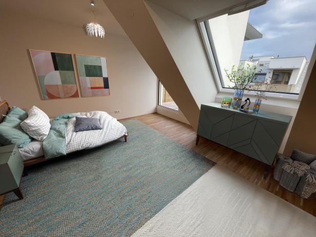 Modern eingerichtetes Schlafzimmer mit großem Fenster und Blick auf die Nachbargebäude im Wohnprojekt Am Langen Felde 24 in Wien-Donaustadt.