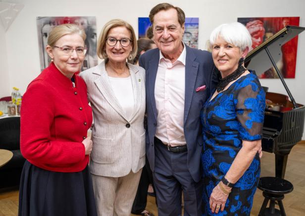 Vier ältere Personen stehen lächelnd nebeneinander in eleganter Kleidung vor einem Flügel.