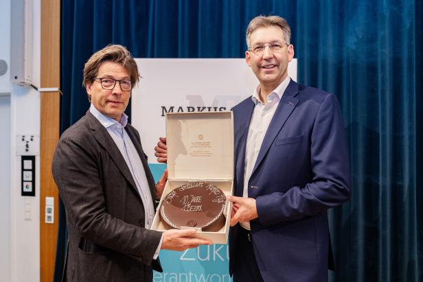 Sacher-Chef Matthias Winkler überreicht eine Torte an Markus Figl. 