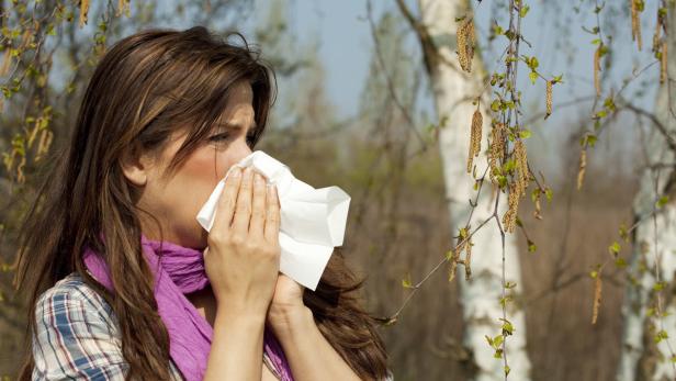 Eine Frau putzt sich wegen einer Allergie die Nase mit einem Papiertaschentuch.
