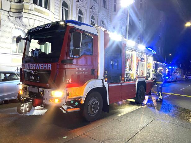 Feuerwehrauto mit eingeschaltetem Blaulicht und Feuerwehrmann bei nächtlichem Einsatz.