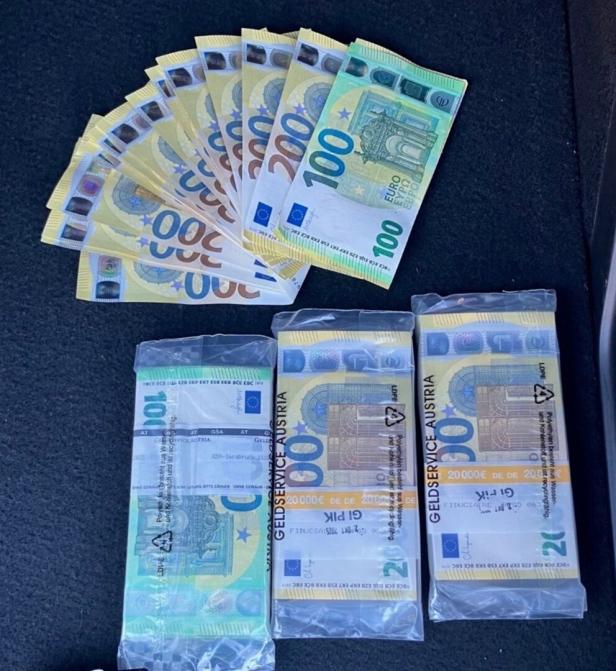 Mehrere 100- und 200-Euro-Scheine liegen aufgefächert sowie in eingeschweißten Bündeln auf dunklem Untergrund.