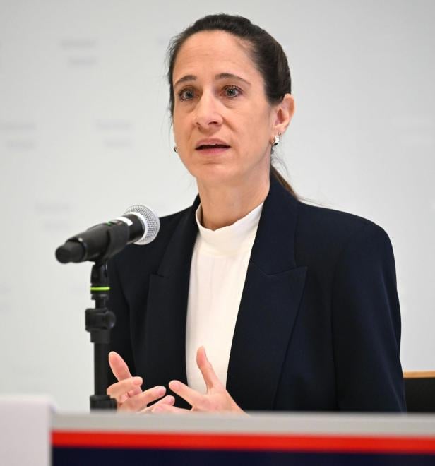 Eine Frau im dunklen Blazer spricht in ein Mikro