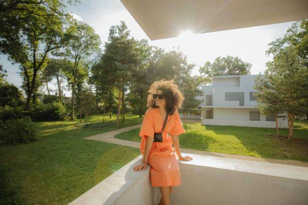 Eine Frau in einem orangefarbenen Kleid in einem Meisterhaus des Bauhaus-Stils