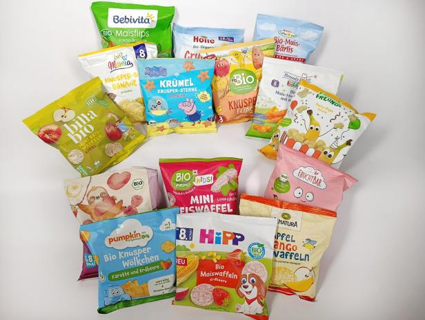 Verschiedene bunte Packungen mit Bio-Snacks für Kinder, darunter Maisflips, Reiswaffeln und Knusperprodukte.