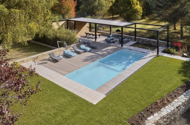 Moderner Pool mit Pergola und Lounge-Bereich, umgeben von stilvollen Möbeln und Pflanzen.