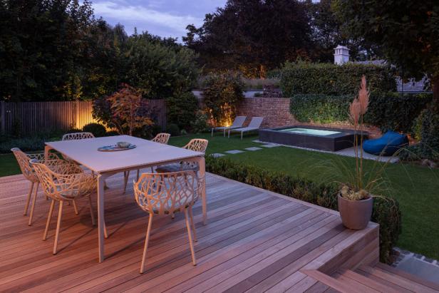 Moderne Terrasse mit Essbereich, Pool, Liegen und stimmungsvoller Gartenbeleuchtung.