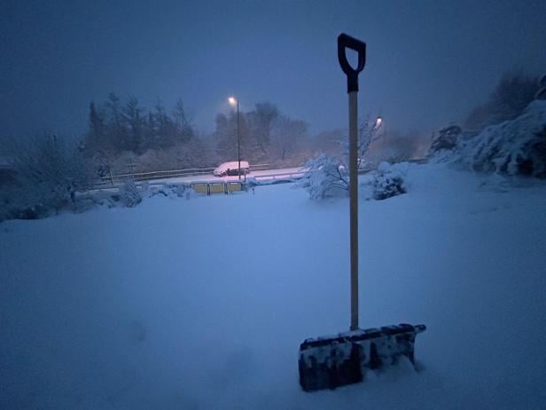 Eine Schneeschaufel steckt im Schnee