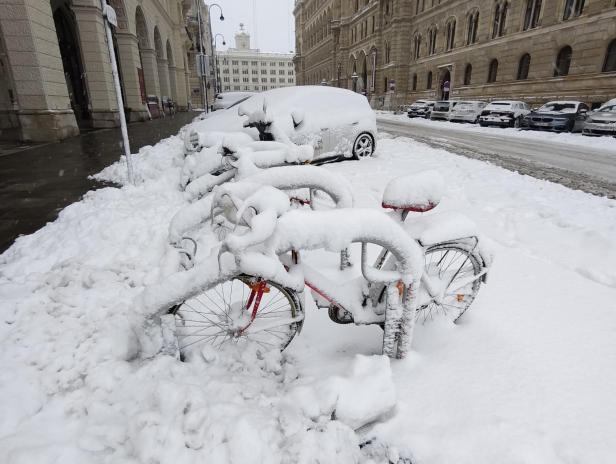 Fahrräder und Autos sind von einer dicken Schneeschicht auf einer Stadtstraße bedeckt.