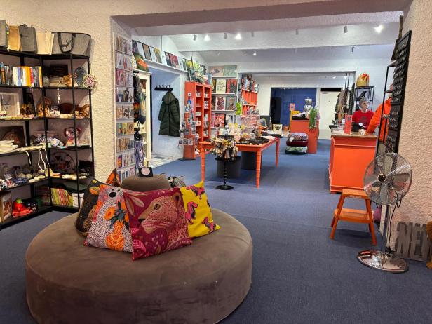 Der Blick in das Geschäftsareal, mit den orangenen Möbeln und blauem Teppichboden.