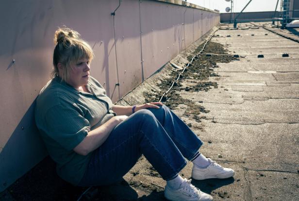 Rosa Herzog (Stefanie Reinsperger) sitzt im Dortmunder "Tatort" nachdenklich an eine Wand gelehnt auf einem Dach.