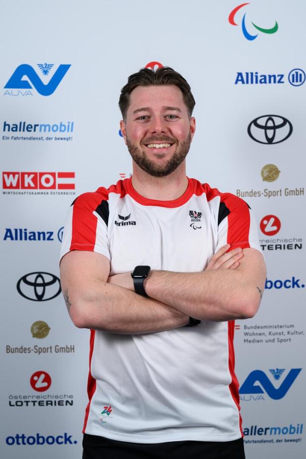 Nico Haberl mit verschränkten Armen, steht vor einem Hintergrund mit Logos verschiedener Organisationen.