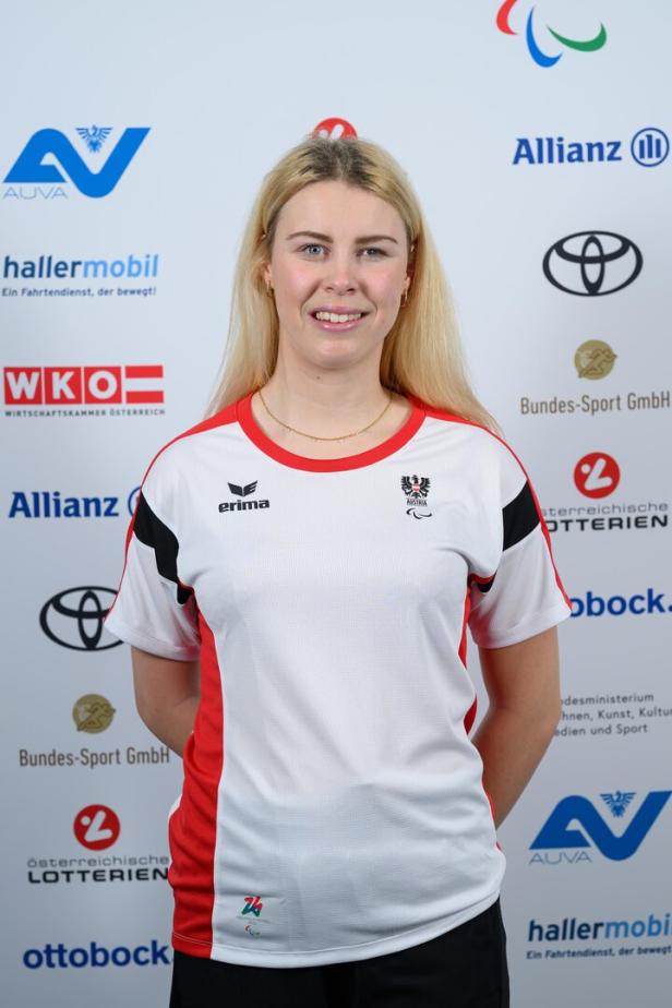 Laura Streng posiert im österreichischen Sporttrikot vor Logos verschiedener Sponsoren.