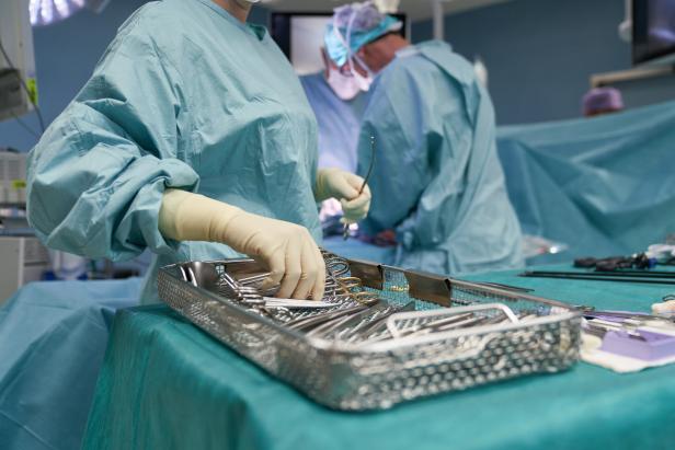 Chirurgisches Team in OP-Kleidung arbeitet mit sterilen Instrumenten an einem Operationstisch.