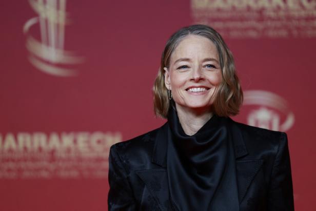 Jodie Foster lächelt vor einem roten Hintergrund beim Marrakech International Film Festival.