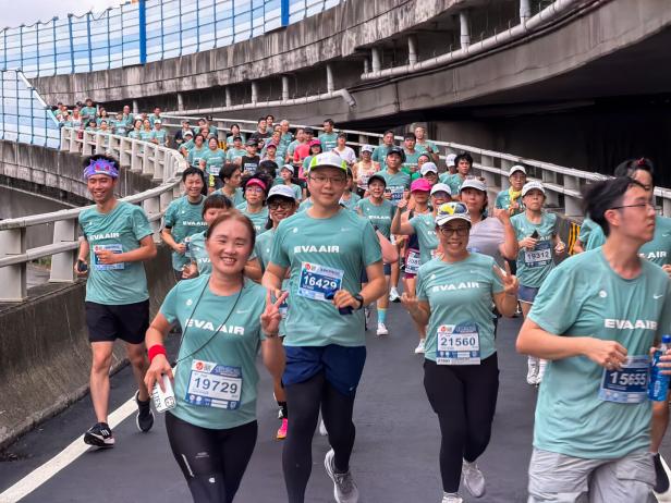 Eine Gruppe von Läufern in grünen EVA Air T-Shirts nimmt an einem Marathon teil.