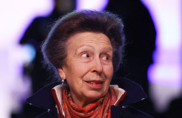 Prinzessin Anne mit hochgestecktem Haar und gemustertem Schal blickt zur Seite.