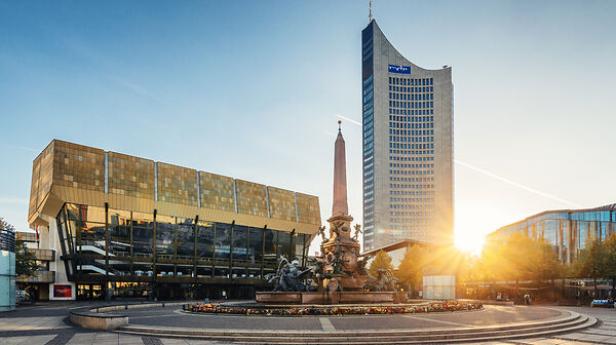 Mendebrunnen mit Brunnenfigur vor dem modernen Gewandhaus und dem City-Hochhaus in Leipzig bei Sonnenuntergang
