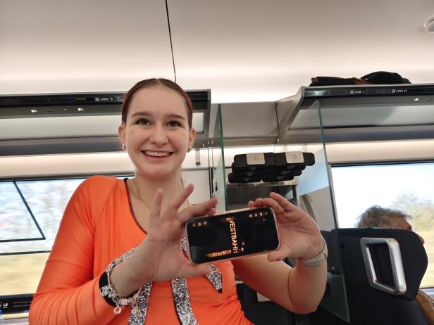 Junge Frau zeigt eine Westbahn-Werbung.