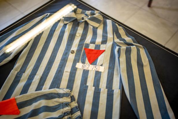 Gestreifte Jacke mit rotem Stoffdreieck und Nummer auf der Brust, dazu passende Hose mit rotem Stoffstück.