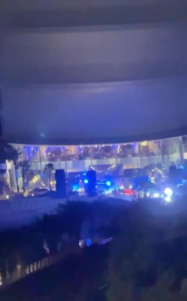 Mehrere Einsatzfahrzeuge mit Blaulicht stehen nachts vor einem modernen, hell erleuchteten Gebäude.