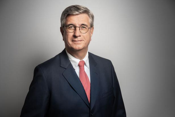 Ein Mann mit Brille und Anzug mit rot-weiß gestreifter Krawatte blickt in die Kamera.