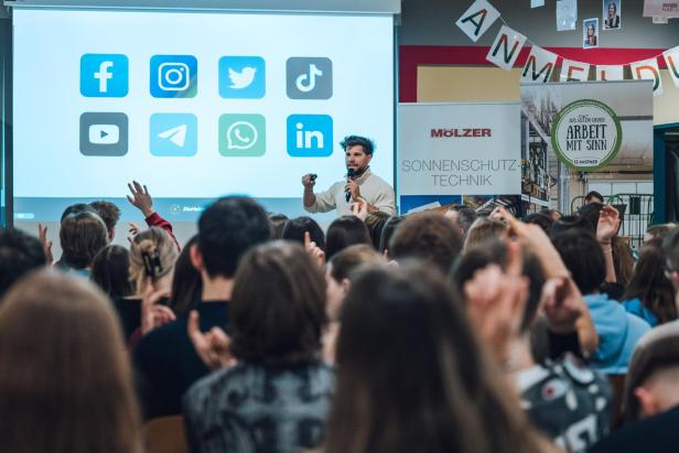 Eine Aufnahme vom Workshop, Lukas Hetzendorfer steht vor einer Gruppe Jugendlicher, einige heben die Hände.
