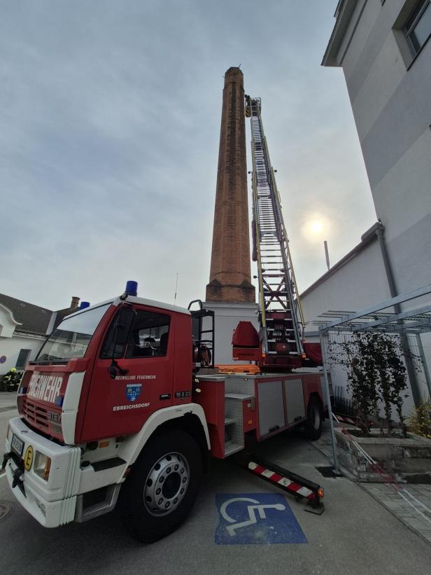 Ein Feuerwehrauto vor einem hohen Schornstein