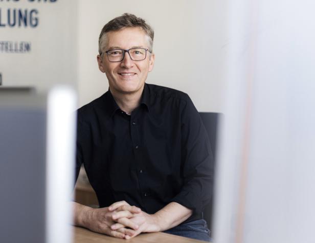 Wolfgang Bliem sitzt  lächelnd an einem Tisch.