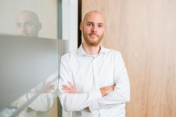 „Wechselboni sind ein starker Hebel, umStefan Spiegelhofer steht mit verschränkten Armen vor einer Holzwand neben einer Glaswand.