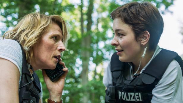"Mordufer": Franziska Weisz und Maria Wördemann mit Schutzwesten, eine telefoniert, im Hintergrund Bäume.