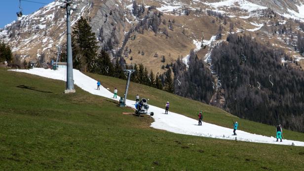 Mehrere Skifahrer fahren einen schneebedeckten Hang hinunter.