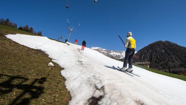 Skifahrer benutzen einen Schlepplift auf einer schneebedeckten Piste.
