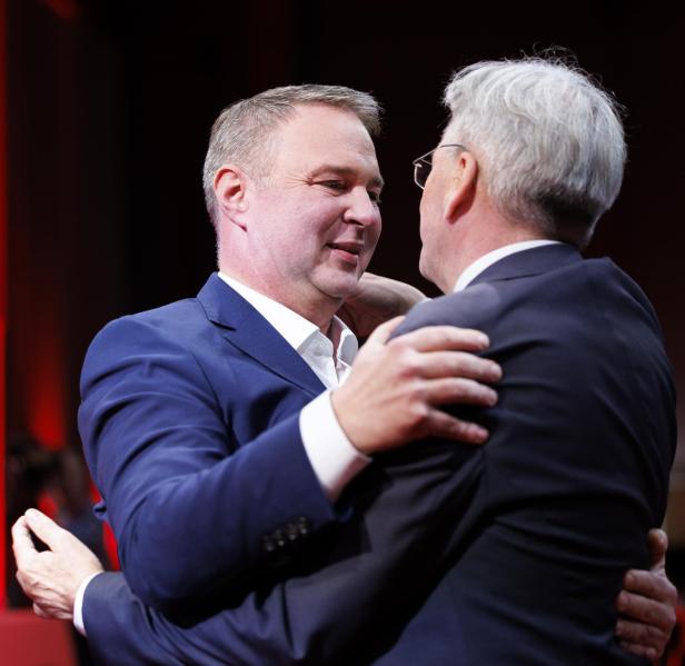 Babler und Kaiser umarmen sich herzlich in einer festlichen Umgebung.