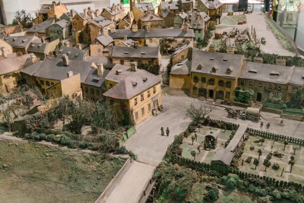 Modell einer historischen Kleinstadt mit vielen Häusern, Straßen, Figuren und einem umzäunten Gartenbereich.