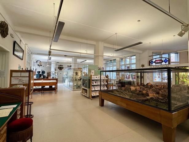 Ein heller Museumsraum mit Vitrinen, Ausstellungsstücken und einem großen Modell einer Stadtlandschaft.