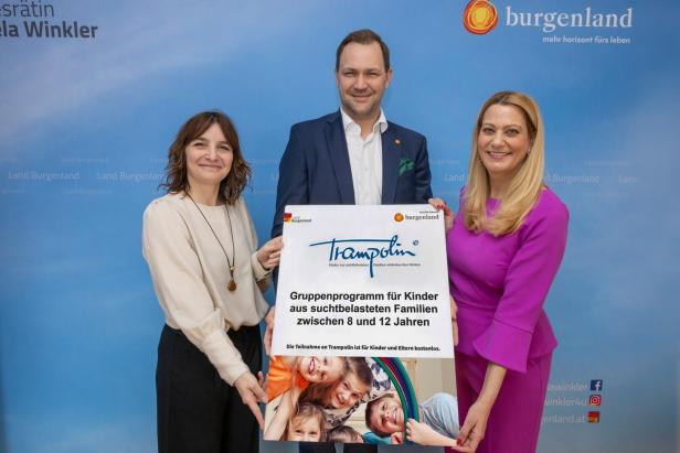 Drei Erwachsene halten gemeinsam ein Plakat für ein Gruppenprogramm für Kinder aus suchtbelasteten Familien.