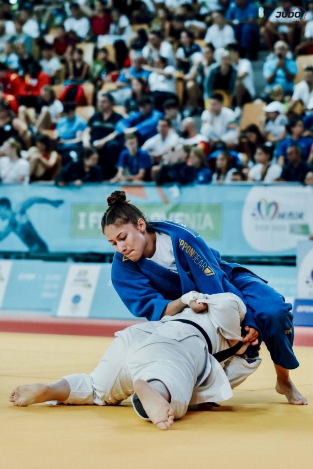 Jael Wernert kämpft im blauen Judogi bei einem internationalen Judo-Wettkampf vor großem Publikum um den Sieg.