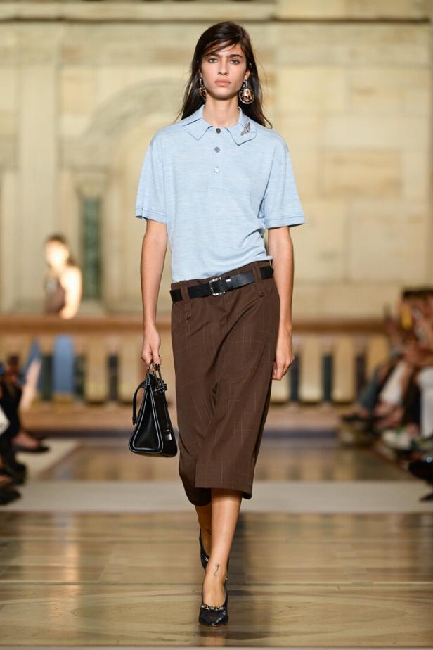 Eine Frau am Laufsteg mit brauner Hose und hellblauer/grauer Bluse