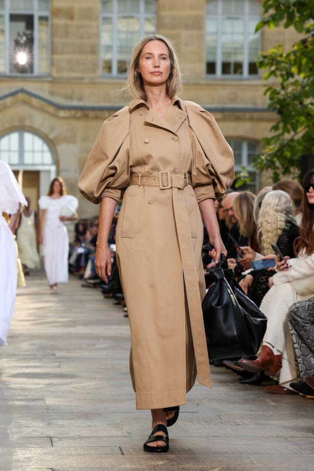 Eine Frau am Laufsteg mit hellbraunem Trenchcoat