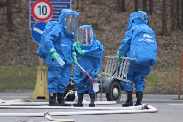 Drei Personen in blauen Schutzanzügen