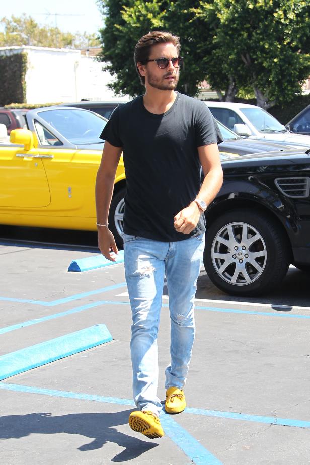 Scott Disick mit Sonnenbrille, T-Shirt und Jeans auf einem Parkplatz.