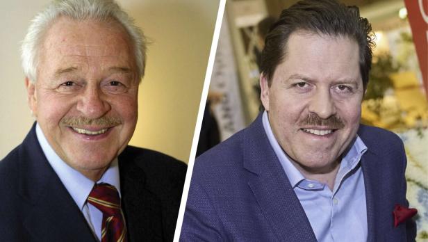 Zwei Männer mit Schnurrbärten lächeln in die Kamera, der linke trägt Anzug mit Krawatte, der rechte ein blaues Sakko.