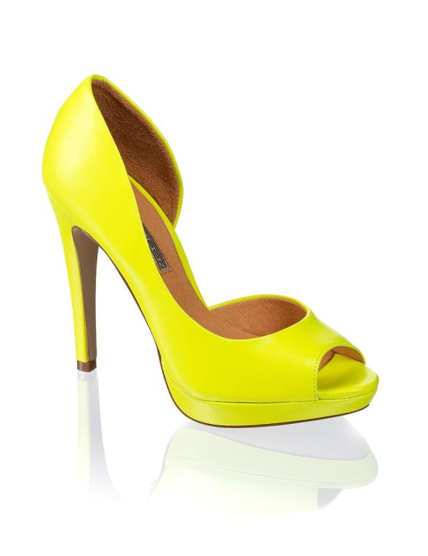 Ein neon-gelber Peep-Toe-Pumps mit hohem Absatz steht auf einer reflektierenden Oberfläche.