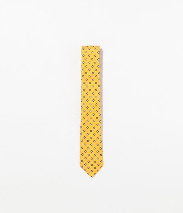Eine gelbe Krawatte mit blauem Rautenmuster auf einem weißen Hintergrund.