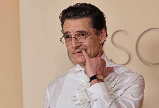 Pedro Pascal mit Brille und weißem Hemd berührt seine Lippe.