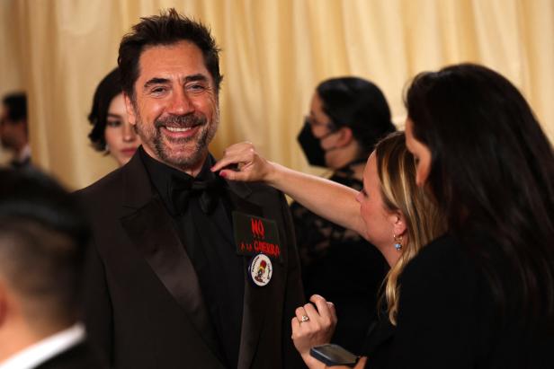 Javier Bardem lächelt, während sein Smoking mit "No a la Guerra"-Anstecker gerichtet wird.