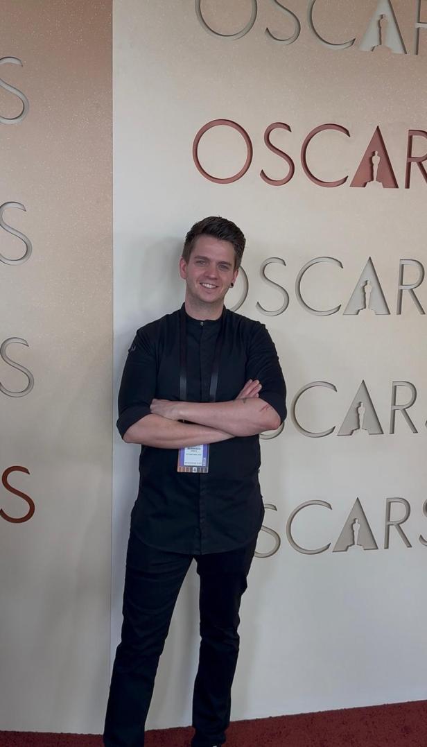 Bernhard Zimmerl steht mit verschränkten Armen in die Kamera lächelnd vor der Ocar-Fotowand.