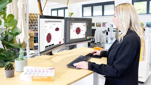 Frau arbeitet am Computer mit 3D-Design-Software für individuell bedruckte Schirme.