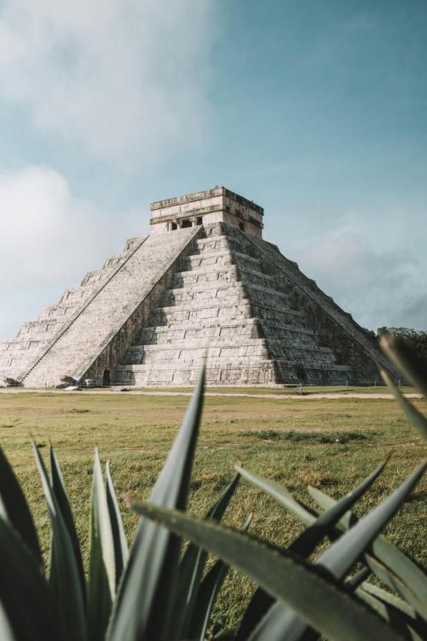 Die Kukulcán-Pyramide von Chichén Itzá vor blauem Himmel und grüner Wiese.